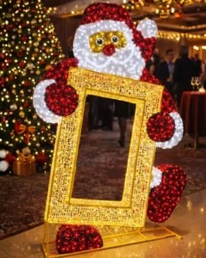 Illuminated Santa holding golden frame near Christmas tree