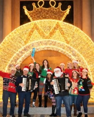 Group in Santa hats under glowing crown display