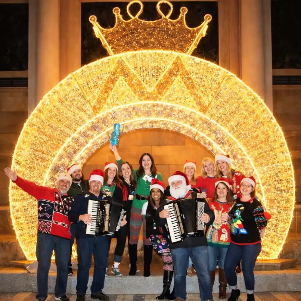 Group in Santa hats under glowing crown display