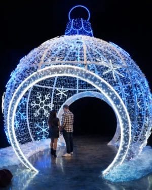 Couple inside giant illuminated Christmas ornament display