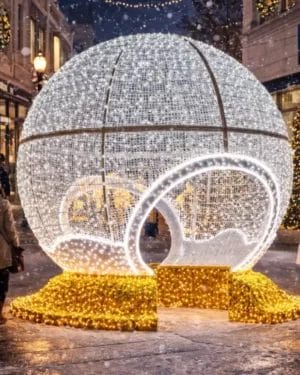 Giant illuminated holiday ornament in snowy shopping street